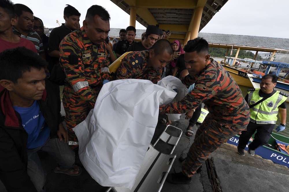 Fire and Rescue Service personnel retrieve the body of Nurain Sufia Zawawi, who drowned along with her two sisters, off Sura Tengah Beach in Dungun December 31, 2018. u00e2u20acu201d Bernama pic