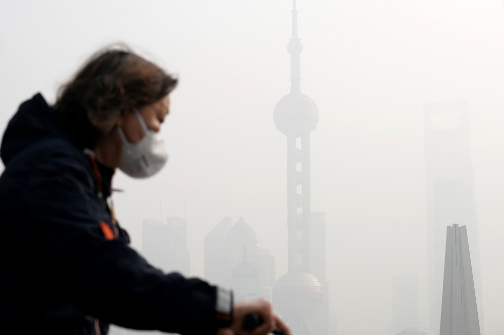 A woman wearing a face mask rides a bicycle on a bridge in front of the financial district of Pudong, which is covered in smog, during a polluted day in Shanghai, China November 28, 2018. u00e2u20acu201d Reuters pic