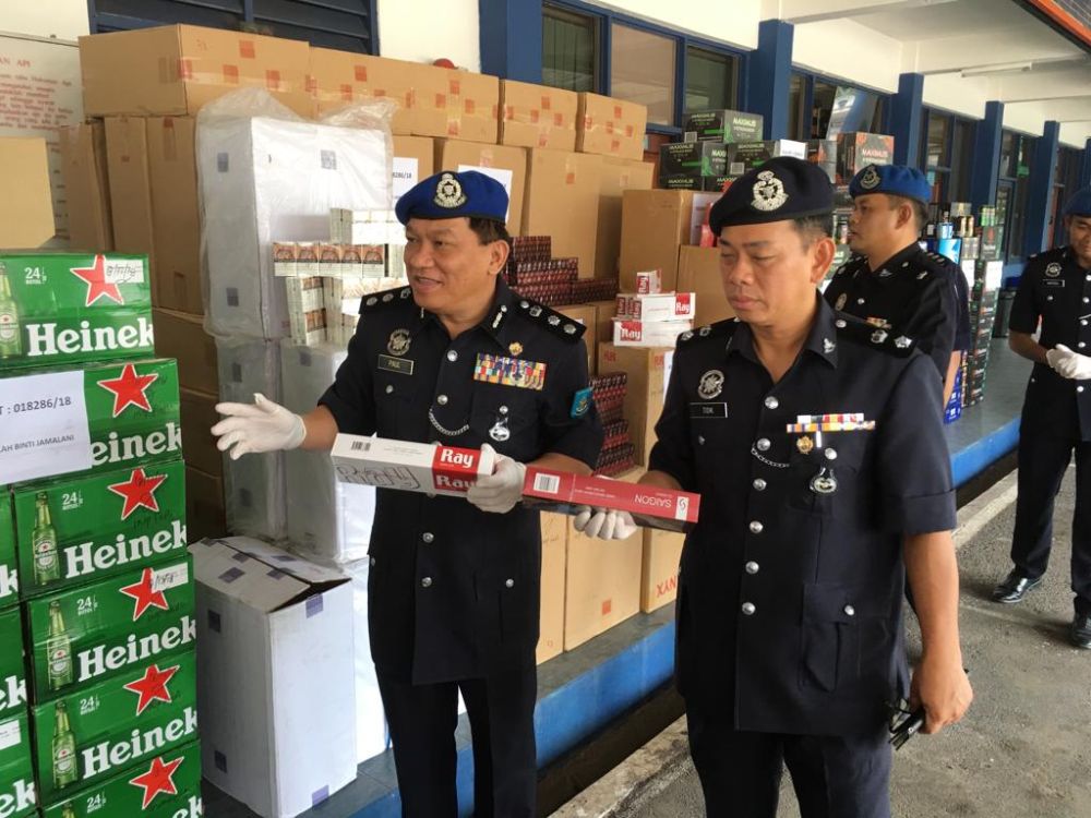 Region Two marine police commander Assistant Commissioner Paul Khiu Khon Chiang (left) explaining on the seized cigarettes and alcohol at the Region Two marine police base in Tampoi. u00e2u20acu201d Picture by Ben Tan
