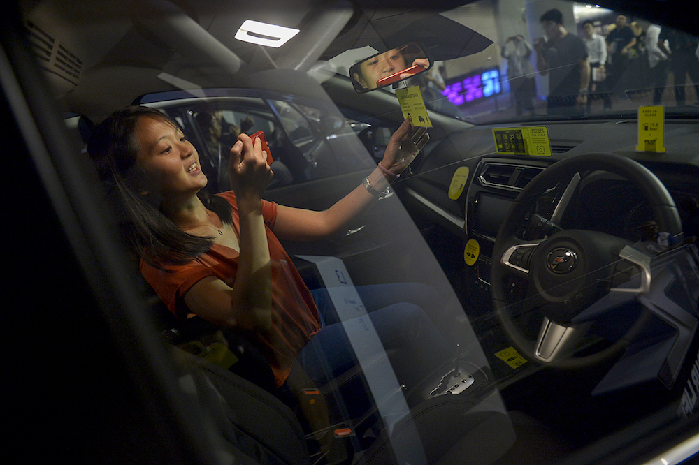 A woman takes pictures inside the new Perodua Aruz during its official launch at MITEC in Kuala Lumpur January 15, 2018. — Picture by Mukhriz Hazim