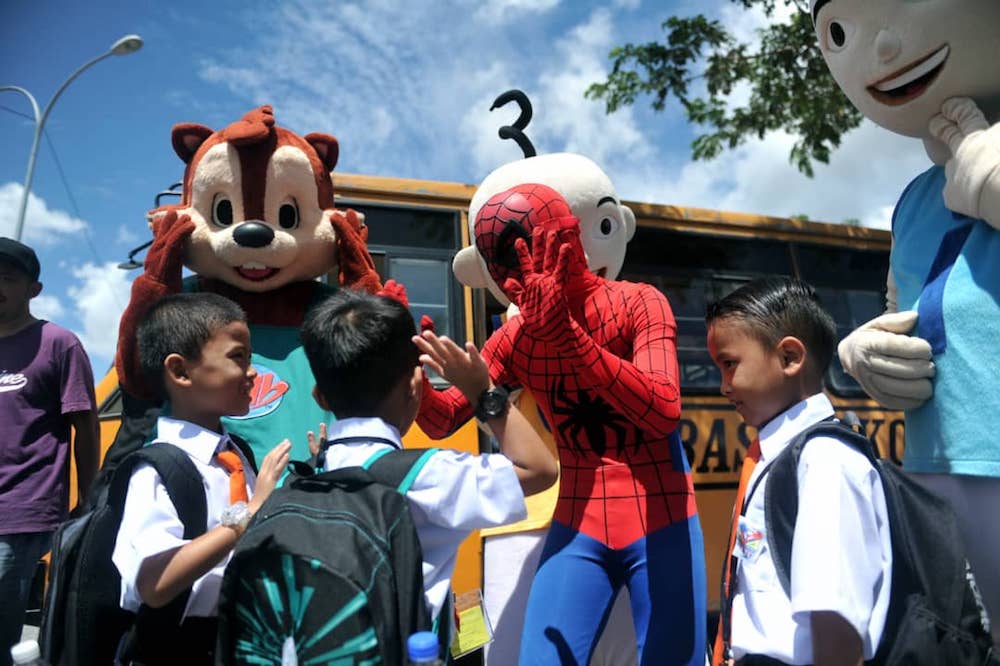 The cartoon characters interact with the newly-enrolled Year One pupils of SK Taman Scientex in Pasir Gudang outside of the school’s entrance today. — Picture by Ben Tan