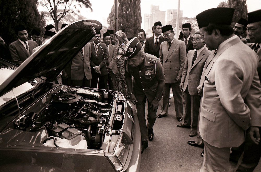 Sultan Iskandar Sultan Ismail examines the engine of the Proton Saga as Tun Dr Mahathir Mohamad looks on in Johor Baru July 10, 1985. — Bernama pic