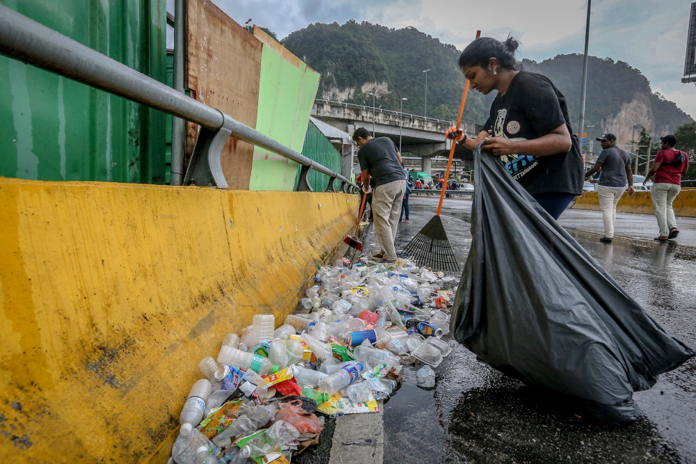 A volunteer clears away rubbish piled up by the roadside during Thaipusam. u00e2u20acu201d Pictures by Firdaus Latif