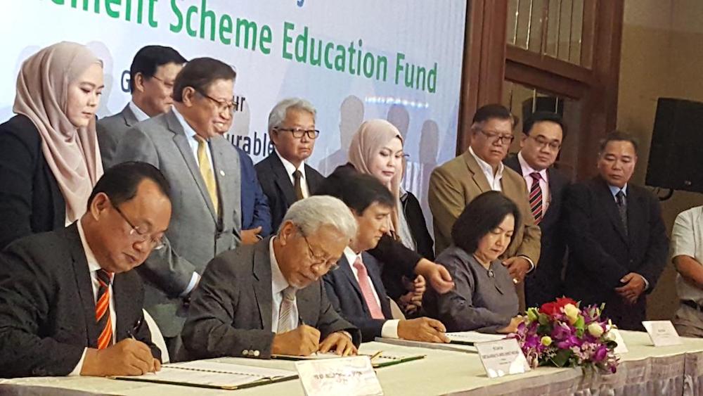 Signing of the MoU in progress: Kennedy Chukpai anak Ugon, Deputy Chief Minister Tan Sri James Masing, Datuk Sharbini Suhaili and Aisah Eden as Chief Minister Datuk Patinggi Abang Johari Openg (standing, 2nd left) looks on. u00e2u20acu201d Picture by Sulok Tawie