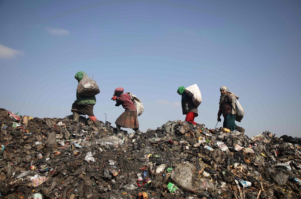Displaced Syrian girls walk across a trash heap carrying on their shoulders bags of collected items at a landfill outside a camp in Kafr Lusin near the border with Turkey in Idlib province in northwestern Syria January 29, 2019. u00e2u20acu201d AFP pic  
