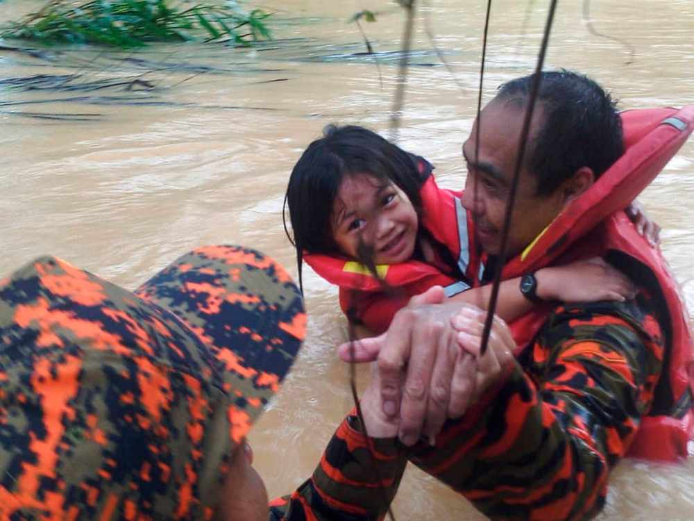 Two firefighters carry a child to a safety in Taritipan, Kota Marudu, Sabah January 26, 2019. u00e2u20acu201d Bernama pic