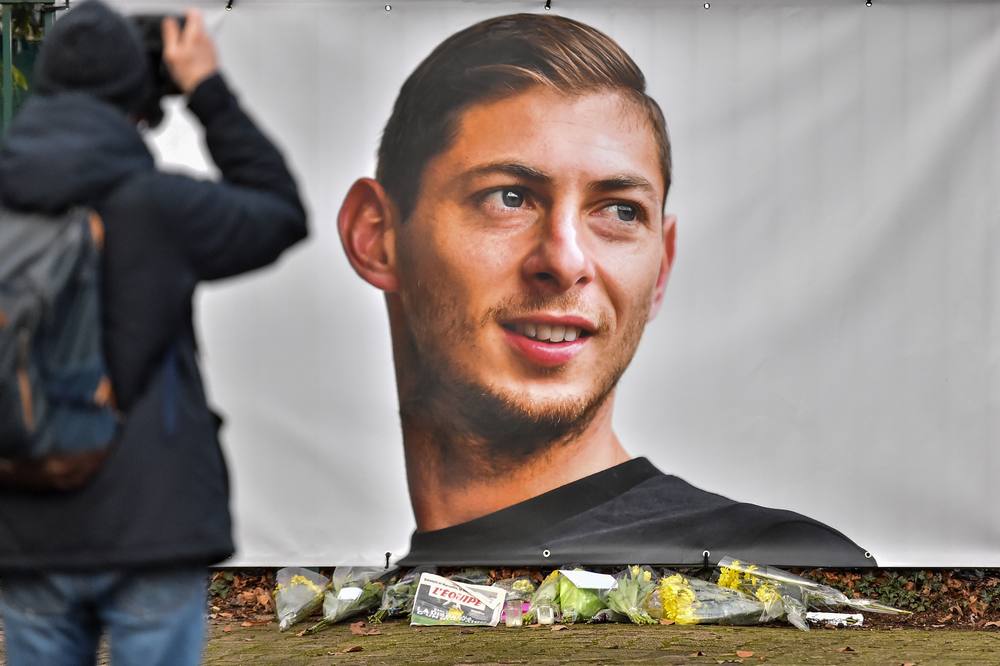 A man takes a picture of flowers and the portrait of Emiliano Sala in front of the entrance of the FC Nantes football club training centre La Joneliere in La Chapelle-sur-Erdre January 23, 2019. u00e2u20acu201d AFP pic