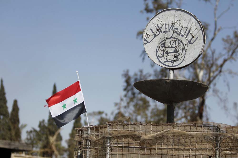 A Syrian national flag flutters next to the Islamic State's slogan at a roundabout where executions were carried out by Isis militants in the city of Palmyra, in Homs Governorate, Syria in this April 1, 2016 file photo. — Reuters pic
