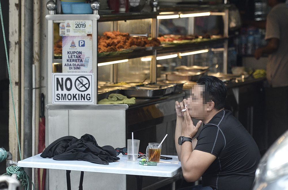 A man smokes outside an eatery in Petaling Jaya January 1, 2019. u00e2u20acu2022 Picture by Miera Zulyana