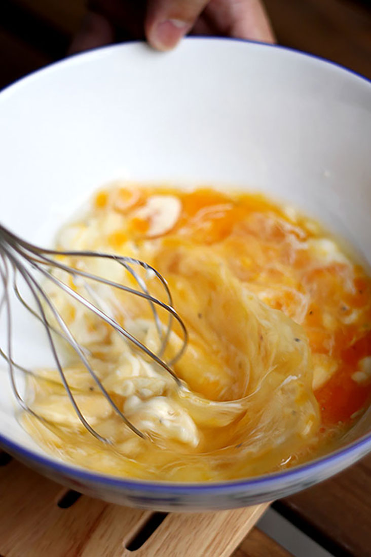 Whisking eggs and Greek yoghurt together.