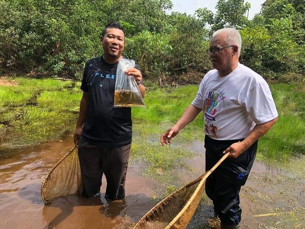 Mohd Ilham Norhakim Lokman (left), pictured with Senggarang assemblyman Khairuddin A. Rahim, holds up a bag containing the Betta persephone at the North Ayer Hitam forest reserve. — Picture by Azlan Sharif