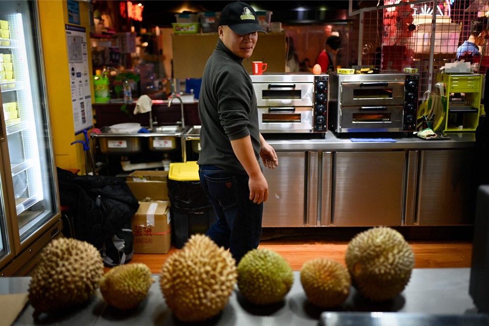 Wang Tao, a durian eatery owner, looking on as a row of the exotic fruit line a countertop at his stall in Beijing January 18, 2019. 