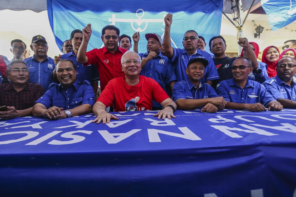 Datuk Seri Najib Razak (centre) and BN's candidate Zakaria Hanafi (seated, third right) meet supporters during a walkabout at the Pasar Tani Beranang in Semenyih February 20, 2019. 