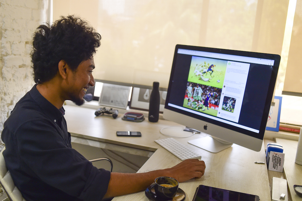 Bangladeshi architect Suhas Nahian reacts as he shows his painting on his computer at his office in Dhaka March 23, 2019. — AFP pic