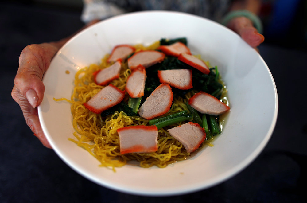 Hawker Leong Yuet Meng, of Nam Seng Noodle House, presents a bowl of wonton noodle soup at her shop in Singapore February 22, 2019. — Reuters pic