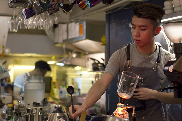 Zac Chan at Studio Caffeine brewing coffee using the siphon method.