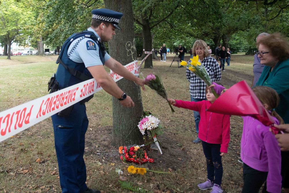 Members of the public hand flowers to a police officer to take over to the Dean Avenue mosque March 17, 2019 in Christchurch, New Zealand, where worshipers were gunned down two days ago. u00e2u20acu201d AFP pic