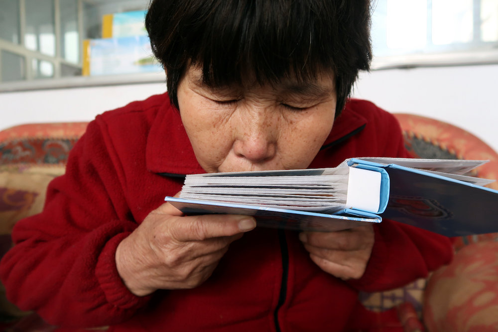 Liu Shuangfeng kisses an album with pictures of her son, who was on board missing Flight MH370, at her house in Handan, Hebei province, China March 1, 2019. — Reuters pic