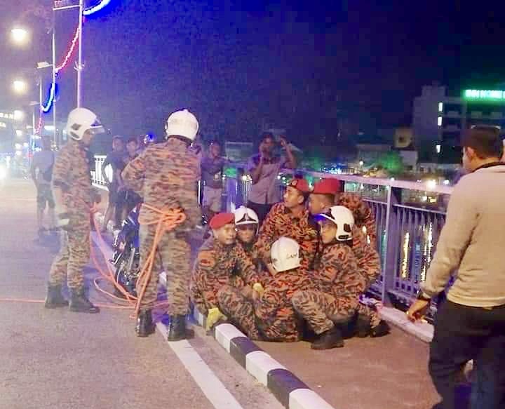 Firemen from the Muar fire station apprehending the 30-year-old man after he was suspected of attempting to jump off the Sultan Ismail bridge in Muar late yesterday. u00e2u20acu201d Picture courtesy of the Johor Fire and Rescue Department