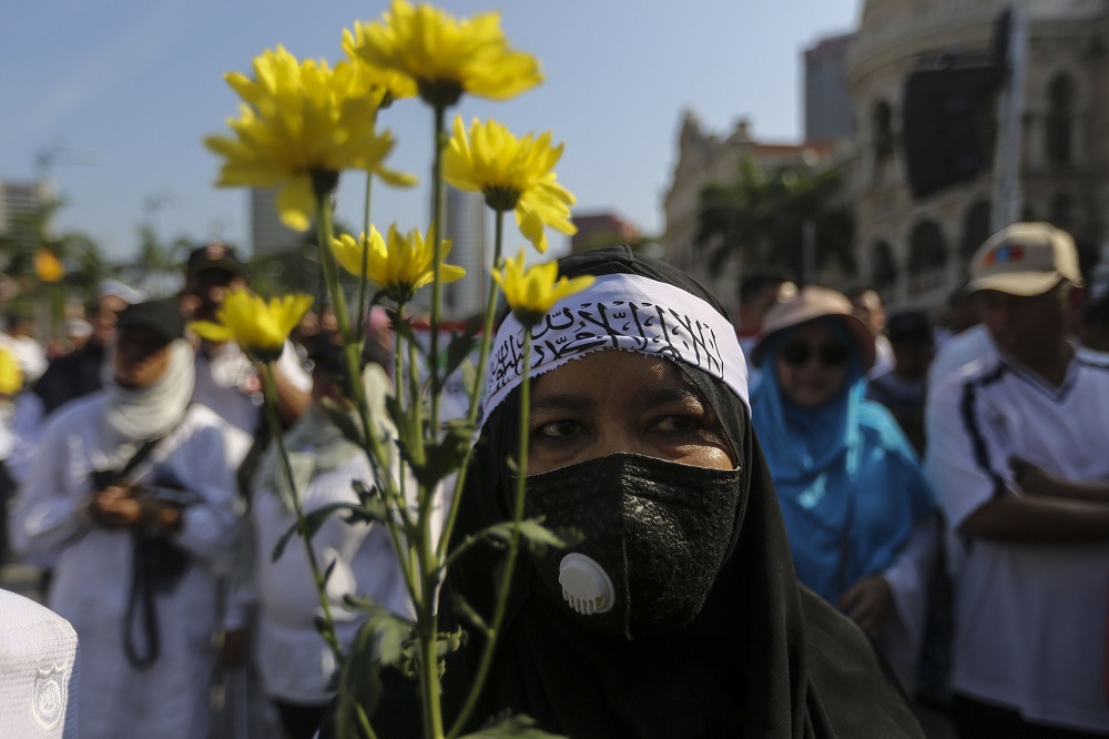 A woman holds some flowers as she marches to Dataran Mardeka during the Solidarity 4 Peace Rally in Kuala Lumpur March 23, 2019. u00e2u20acu201d Picture by Yusof Mat Isa