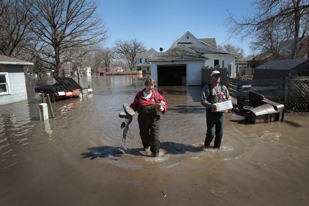 Bill Peeler (right) helps his friend Kathy Drummond remove items from her flooded home March 20, 2019 in Hamburg, Iowa. u00e2u20acu201d Scott Olson/Getty Images pic via AFP