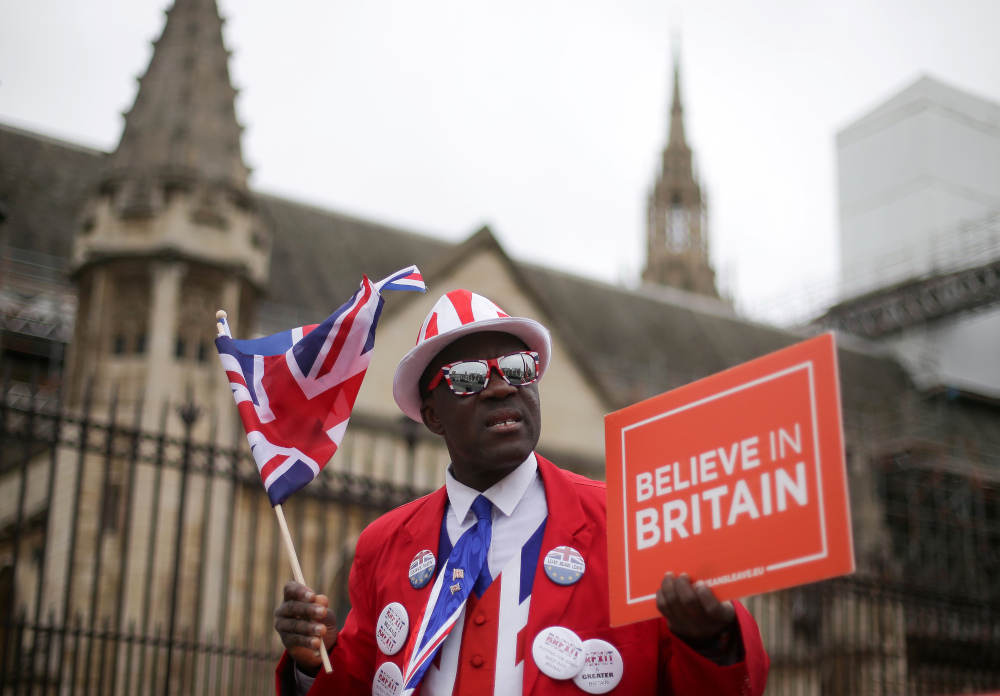 Pro-Brexit activist Joseph Afrane holds a placard and waves a Union flag as he demonstrates outside the Houses of Parliament in central London March 20, 2019. u00e2u20acu201d AFP pic 