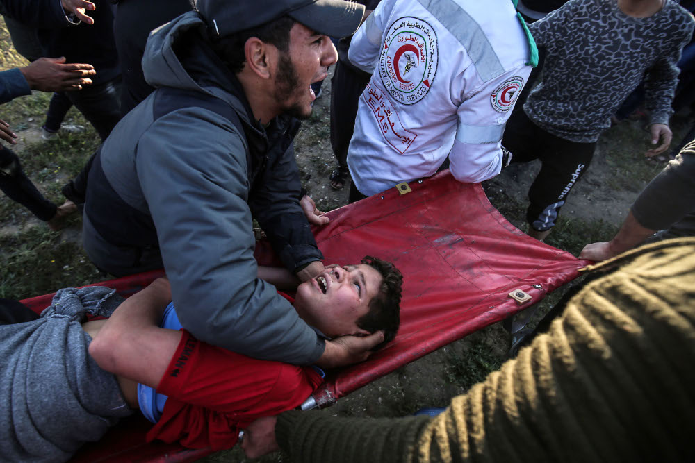 A Palestinian man carries an injured youth at the border fence with Israel east of Gaza City March 22, 2019. u00e2u20acu201d AFP pic 