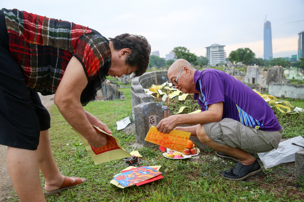 Two family members preparing offerings for their ancestors. — Picture by Choo Choy May