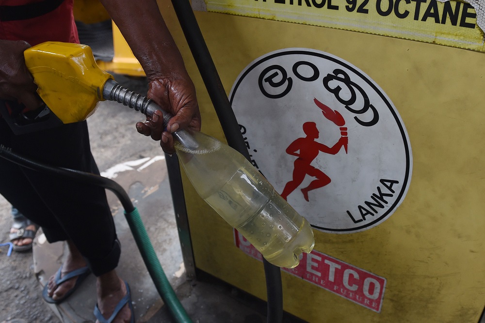 A Sri Lankan petrol pump attendant fills a bottle at a petrol station in Colombo May 10, 2018. u00e2u20acu2022 AFP pic