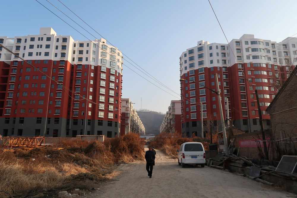 A man walks near a shantytown to be redeveloped, in front of apartment buildings, in Fu county in the south of Yanan, Shaanxi province, China January 2, 2019. u00e2u20acu201d Reuters pic