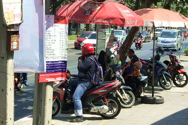 'Motosai lapjang' or motorcycle taxi riders waiting for passengers under a makeshift shelter.