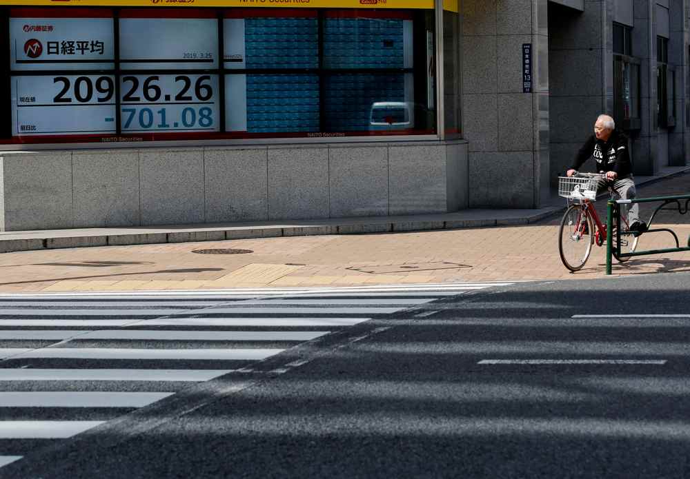 A man in a bicycle stops in front of an electronic board showing the Nikkei stock index outside a brokerage in Tokyo, Japan March 25, 2019. u00e2u20acu201d Reuters pic