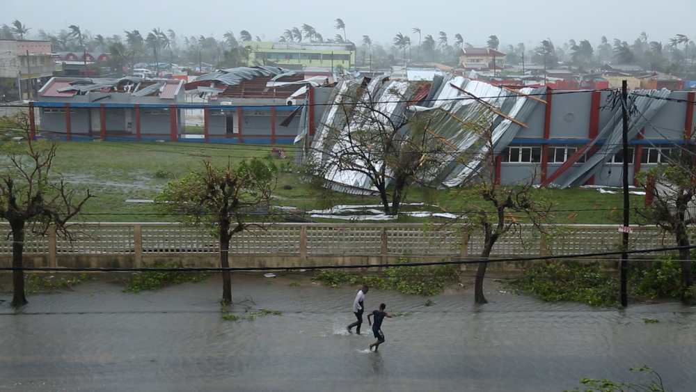 People walk down a flooded road next to buildings damaged by Cyclone Idai in Beira, Mozambique, March 17, 2019 in this still image taken from a social media video March 18, 2019. u00e2u20acu201d Reuters pic