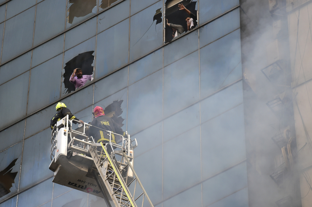 People trapped inside a burning office building gesture at Bangladeshi firefighters for help in Dhaka on March 28, 2019. u00e2u20acu201d AFP pic 