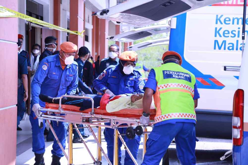 Emergency medical staff bringing a primary school student from SK Tanjung Puteri Resort to receive treatment for breathing difficulties at the Taman Pasir Putih multipurpose hall in Pasir Gudang today. u00e2u20acu201d Picture by Roysten Rueben