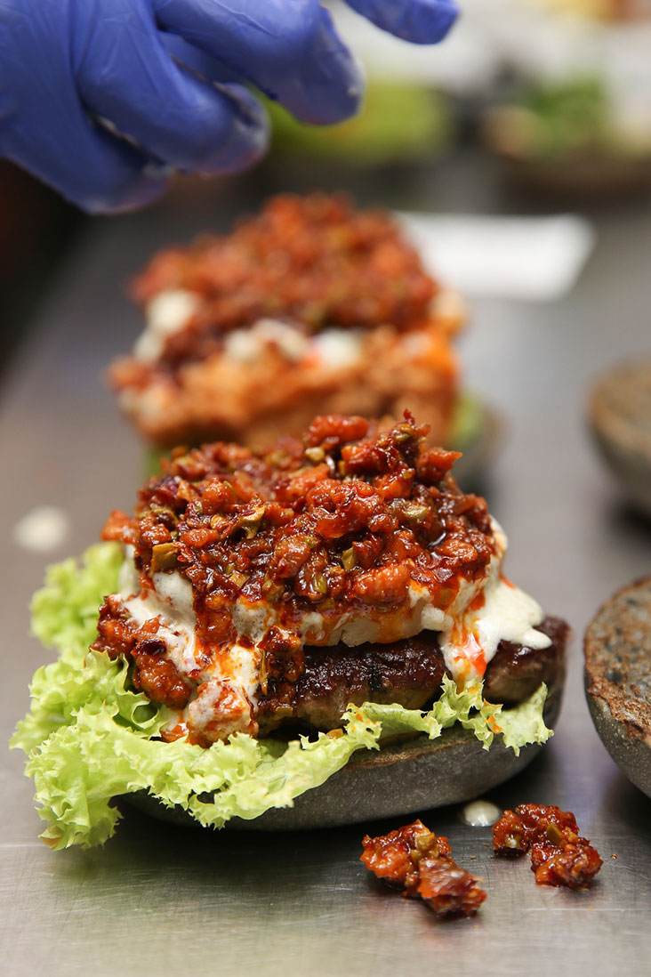 A dollop of 'sambal peta'i crowns the burger before the bun is placed on top.
