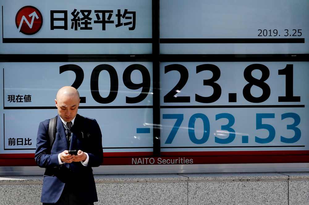 A man stands in front of an electronic board showing the Nikkei stock index outside a brokerage in Tokyo, Japan March 25, 2019. u00e2u20acu201d Reuters pic