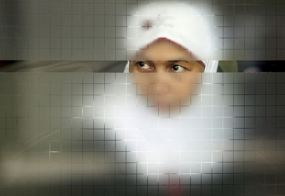 A migrant worker looks on from behind a glass door as she waits for her documents to be processed after arriving from Malaysia, at a special terminal for migrant workers in the Soekarno-Hatta Airport in Jakarta October 28, 2009. u00e2u20acu201d Reuters pic