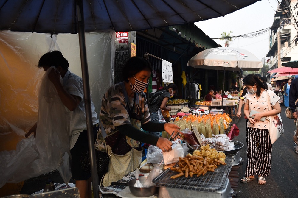A woman, wearing a face mask, prepares her food stall in a market in the northern Thai province of Chiang Mai April 2, 2019. — AFP pic