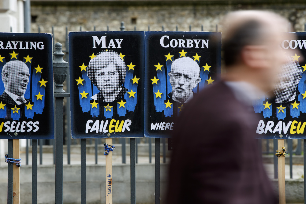 Pedestrians walk past placards featuring Britainu00e2u20acu2122s Prime Minister Theresa May and opposition Labour party leader Jeremy Corbyn near the Houses of Parliament in central London April 3, 2019. u00e2u20acu201d AFP pic 