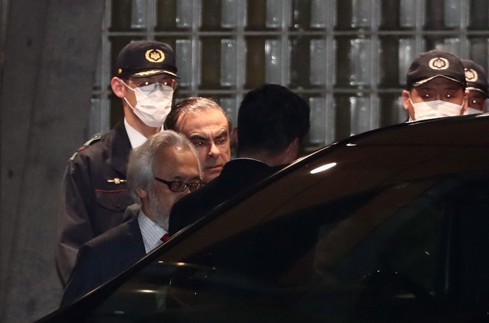 Former Nissan chairman Carlos Ghosn (centre) is escorted as he walks out of the Tokyo Detention House following his release on bail in Tokyo on April 25, 2019. u00e2u20acu201d AFP pic