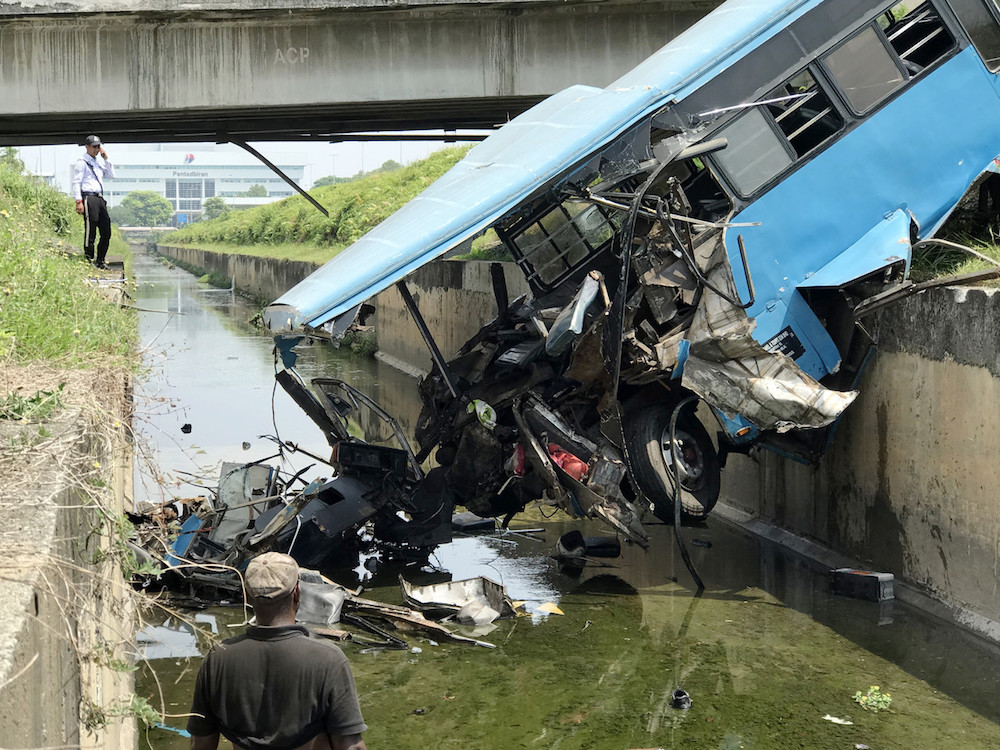 The wreckage of the bus lies in a monsoon drain near MASkargo Complex in Sepang April 7, 2019. u00e2u20acu201d Bernama pic