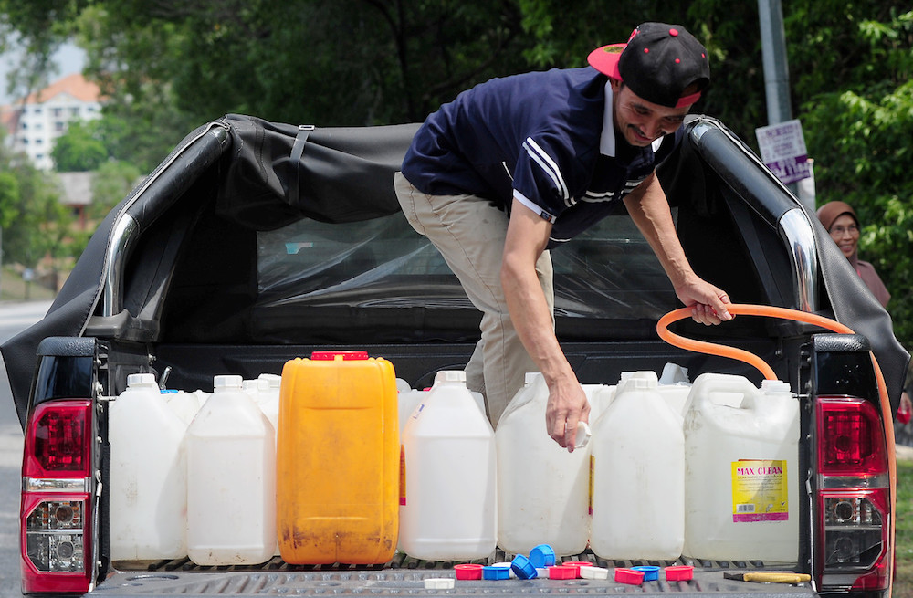 A man fills containers with water at a public water tap in Shah Alam April 25, 2019. u00e2u20acu201d Bernama pic
