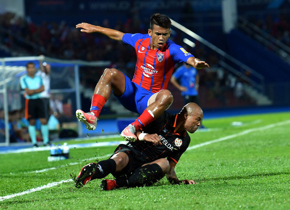 Muhammad Safawi Rasid of JDT is tackled by Thiago Junio De Aquino of Felda United at the Tan Sri Hassan Yunos Stadium in Larkin, Johor Bahru, April 5, 2019. u00e2u20acu201d Bernama pic
