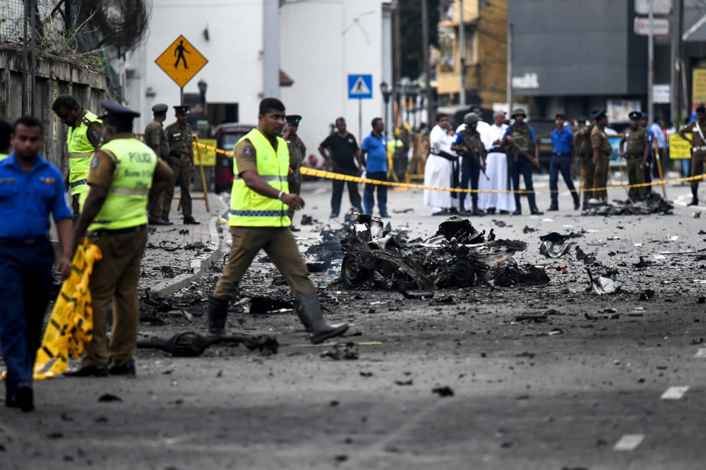Sri Lankan security personnel inspect the debris of a car after it explodes when police tried to defuse a bomb near St Anthonyu00e2u20acu2122s Shrine as priests look on in Colombo April 22, 2019.u00e2u20acu201d AFP pic