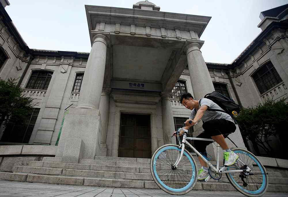 A man gets on a bicycle in front of the Bank of Korea in Seoul August 9, 2012. u00e2u20acu201d Reuters pic