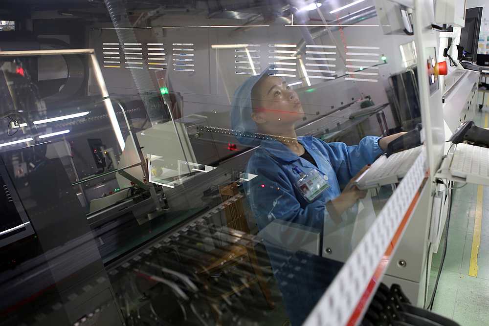 An employee on the production line of an electronics factory is seen reflected on equipment in Jiaxing, Zhejiang province, China April 2, 2019. u00e2u20acu201d Reuters pic