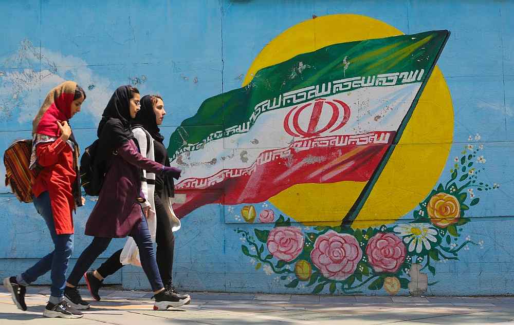 Young girls walk in front of a mural showing the Iranian national flag in the centre of Tehran, April 23, 2019. The US announced the day before it was calling an end to six-month waivers for oil sanctions on Iran. u00e2u20acu201d AFP pic