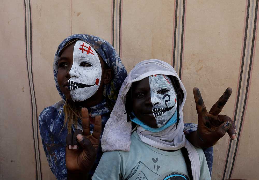Sudanese girls with half painted faces make victory signs as they watch protesters demonstrating outside the defence ministry compound in Khartoum April 25, 2019. u00e2u20acu201d Reuters pic