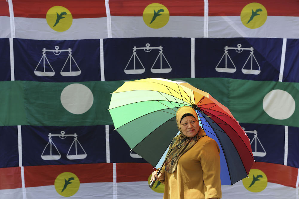 A woman walks past Umno, Barisan Nasional and PAS flags in Pekan Kuala Sawah, Rantau April 10, 2019. u00e2u20acu201d Picture by Yusof Mat Isa